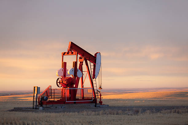 A pumpjack on the prairie. Alberta, Canada. This oil rig is located near Turner Valley, Alberta in an area where the oil industry is a major economic driver. Additional themes include crude oil, oil field, oilsands, prairie, rural, gas, fossil fuel, environment, energy, economy, rolling hills, scenic, southern alberta, red, agriculture, industry, equipment, and autumn.
